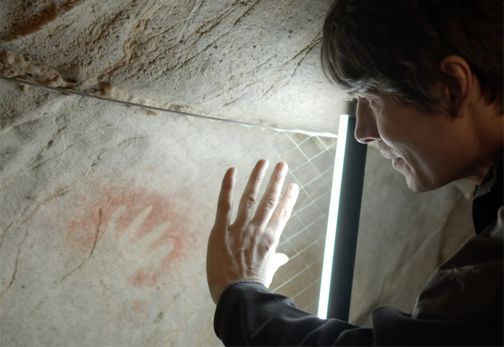 Brian Cox staring at a child's hand print made at least 35.000 years ago in Cantabria Cave, Spain.